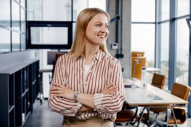 Genç bir kız modern bir çalışma alanında duruyor.