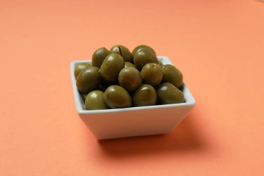 Beyaz kasede pembe arka planda zeytinler, yakın plan.