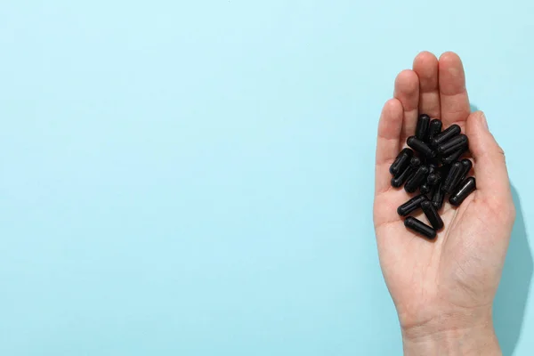 Tablets of activated carbon in the hand on a light background