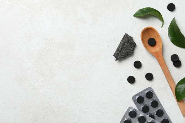 A wooden spoon with activated charcoal tablets and leaves