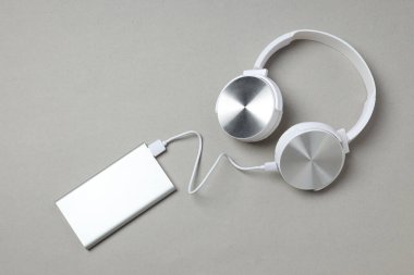 Gri arka planda Powerbank ve kulaklıklar, üst görünüm
