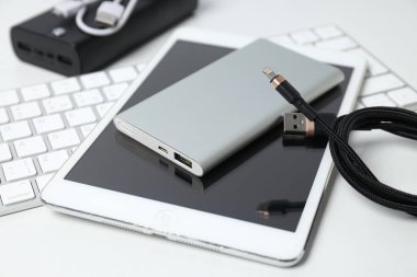 Beyaz arkaplanda Powerbank, kablo ve tablet, kapatın