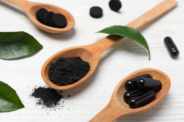 Tahta kaşık ve yapraklarla aktif kömür tabletleri