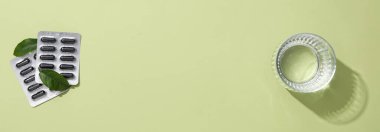 Aktif karbon tabletleri ve arka planda bir bardak su.