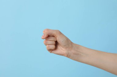 Açık mavi arka planda kadın eli yumruğa yapıştı.