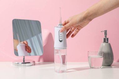 Sulama, ayna ve kadın eli pembe arka planda.