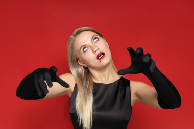 Cadılar bayramı vesilesiyle kırmızı arka planda zombi kostümü giymiş genç bir kız..