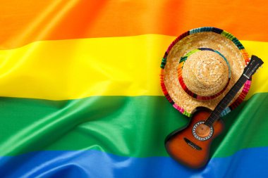 Lgbt bayrağının arka planında gitar ve sombrero.