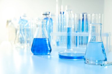 Cam mataralar ve beyaz zemin üzerinde sıvı bulunan test tüpleri.