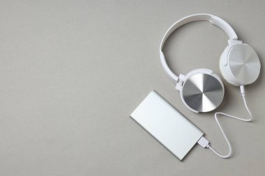 Gri arkaplanda Powerbank ve kulaklıklar, metin için boşluk