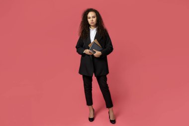 Gözlüklü çekici bir genç kız ve kırmızı arka planda siyah bir takım elbise.