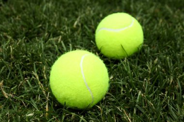Yeşil çimlerin üzerinde iki tenis topu, yaklaş.