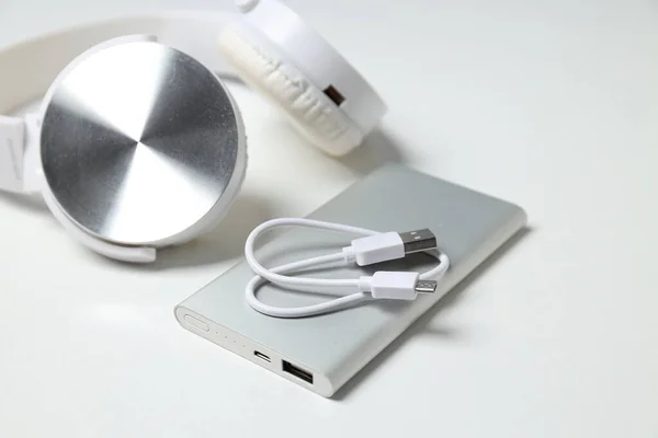 Powerbank, cord and headphones on white background, close up