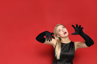 Cadılar bayramı vesilesiyle kırmızı arka planda zombi kostümü giymiş genç bir kız..