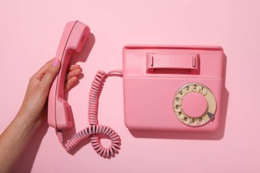 Pembe telefon ve pembe arka planda kadın eli, üst manzara.