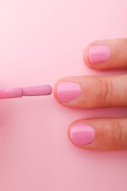 Pembe arka planda manikürlü kadın eli.