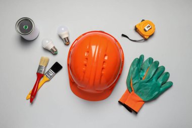 İnşaat miğferi, fırçalar, boya ve ampuller beyaz arka planda, üst manzara