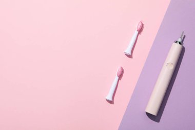 Pembe ve mor arkaplanda elektrikli diş fırçası, metin için boşluk