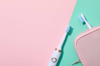 Elektrikli diş fırçaları ve pembe arkaplan üzerindeki çanta, metin için boşluk