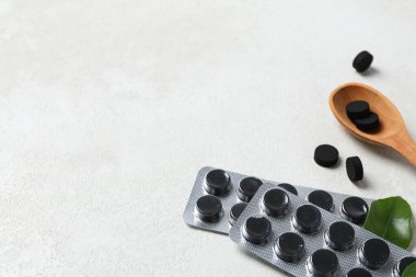 Aktif kömür tabletleri ve yaprakları olan tahta bir kaşık.