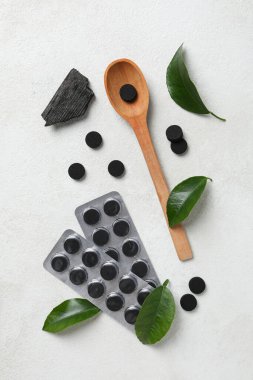 Aktif kömür tabletleri ve yaprakları olan tahta bir kaşık.