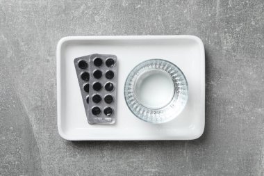 Aktif kömür tabletleri ve beyaz bir kasede bir bardak su.