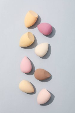 Gri arkaplanda kozmetik süngerler, üst görünüm