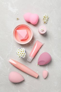 Dekoratif kozmetik ürünleri ve ışık arka planında çiçekler, üst görünüm