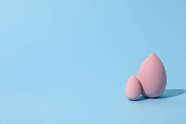 Mavi arkaplanda kozmetik süngerler, metin için boşluk