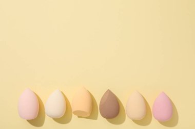 Sarı arkaplanda kozmetik süngerler, metin için boşluk