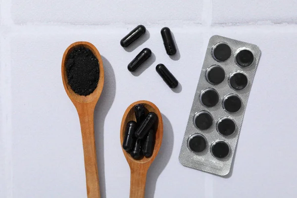 Aktív Faszén Tabletták Fából Készült Kanalakkal Könnyű Háttérrel — Stock Fotó