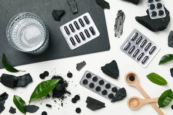 Activated charcoal tablets with wooden spoon and leaves