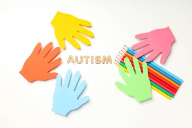 Beyaz arka planda kalemleri olan çok renkli kağıt eller. Dünya otizm günü konsepti