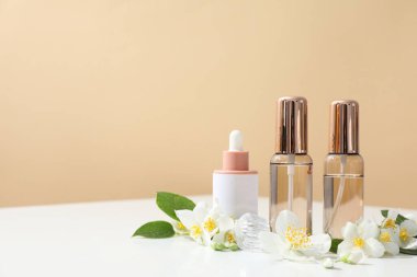 Bej arka planda yasemin çiçekleri ve parfüm şişeleri, metin için boşluk