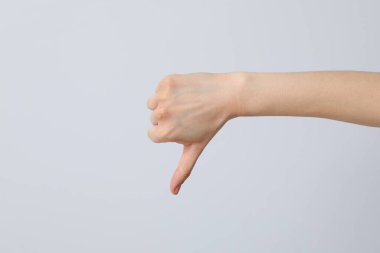 Gri arka planda parmağını gösteren bir kadın el.