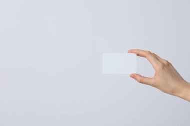 Arka planda beyaz, boş bir kağıt parçası olan bir kadının ellerinde.