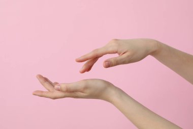 Açık pembe arka planda kadın elleri