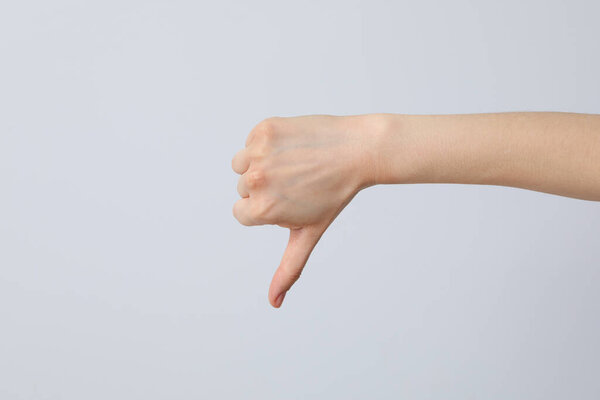 Женская рука показывает пальцем вниз на сером фоне