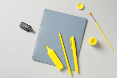 Gri arkaplanda defter, kalem ve boyalar, üst görünüm