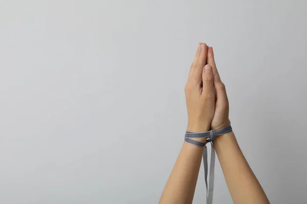 Hands tied with a ribbon on a light background.
