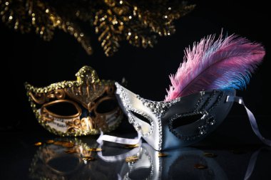 Karnaval maskeleri ve siyah arkaplanda tüy