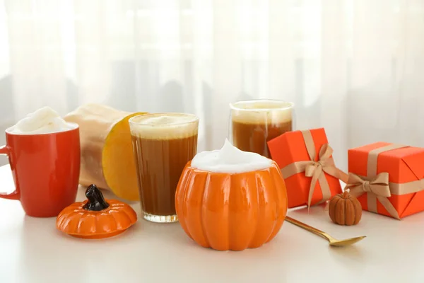 Pumpkin coffee, gift boxes and pumpkins on light background