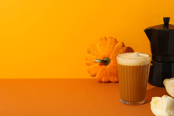 Pumpkin coffee and pumpkins on orange background, space for text