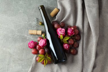 Cam şişe, güller ve üzümler gri arka planda, üst manzara