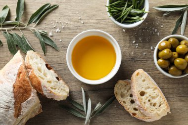 Zeytinyağı, zeytin ve ekmek dilimleri ahşap arka planda, üst manzara