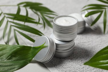 Havlu kremalı kavanozlar ve gri arka planda yapraklar