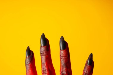 Sarı arka planda bir canavarın ürkütücü, kırmızı elleri.