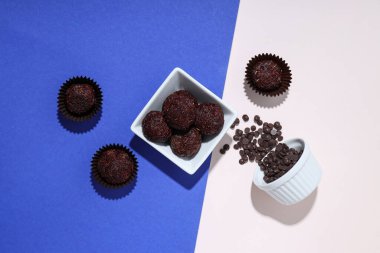 Mavi ve beyaz arka planda kaselerde Brigadeiro ve çikolata parçacıkları, üst görünüm