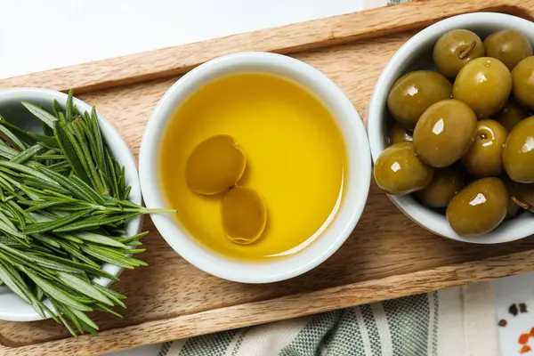 Zeytin dalları, yağlar ve zeytinler kaselerde, beyaz arka planda havlu, kapat