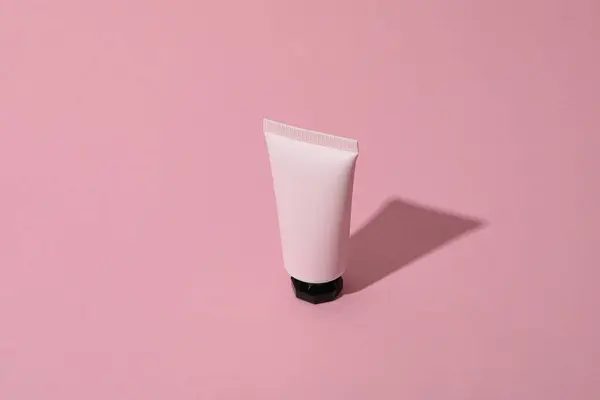 Pink tube with cream on pink background